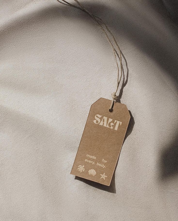 a tag that says sact hanging from a string on top of a white sheet