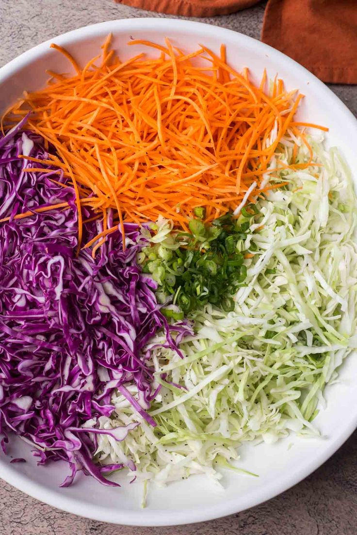 shredded carrots, cabbage and celery in a white bowl on a table