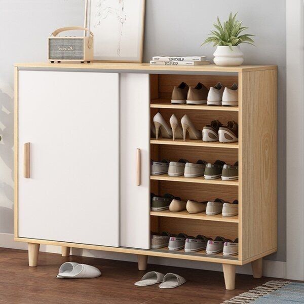 a shoe rack with shoes on it next to a white wall and wooden flooring