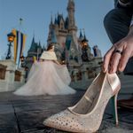 a woman is trying to put on her wedding shoes in front of the cinderella castle