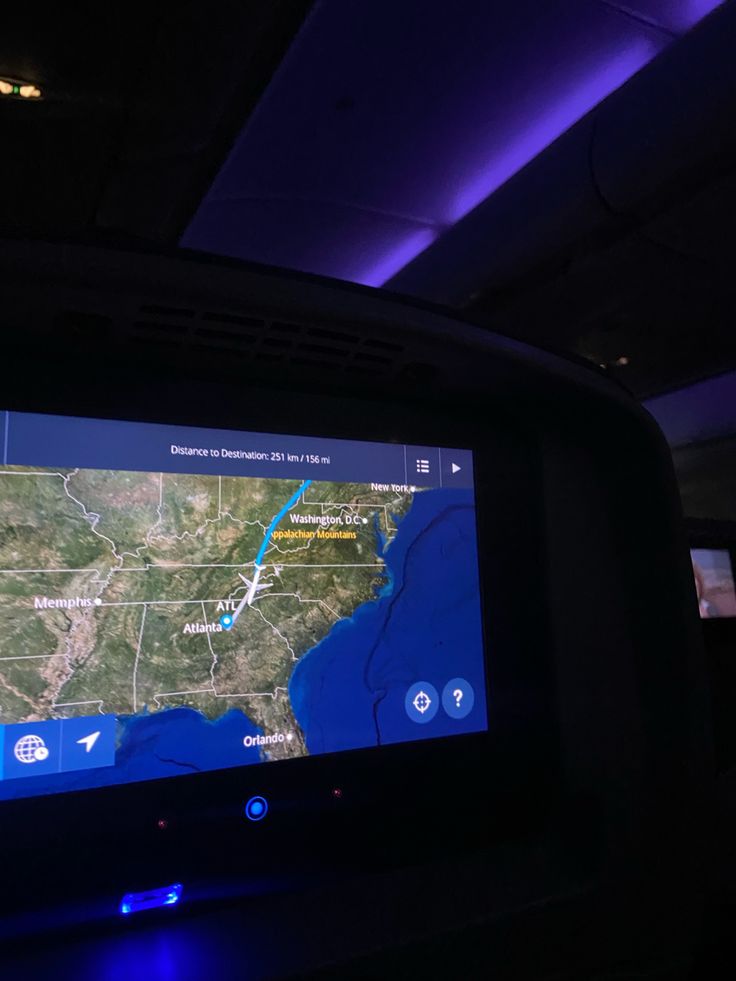 an airplane dashboard with the map on it's screen and lights in the background