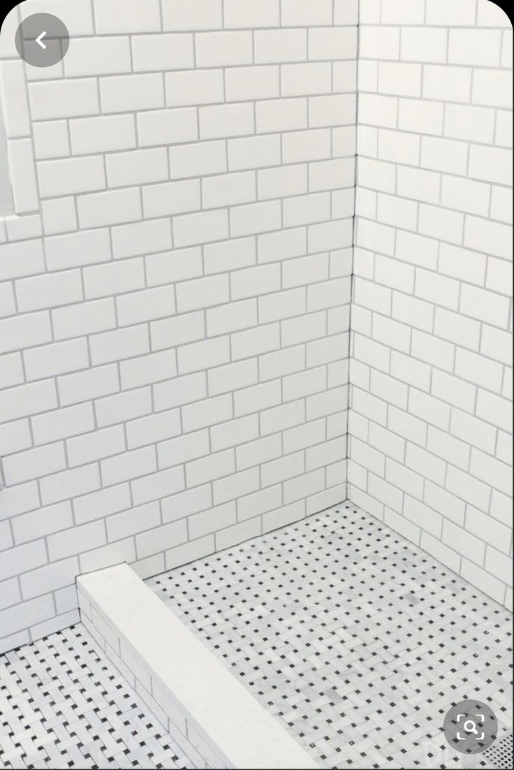 a white tiled shower stall with black and white tiles