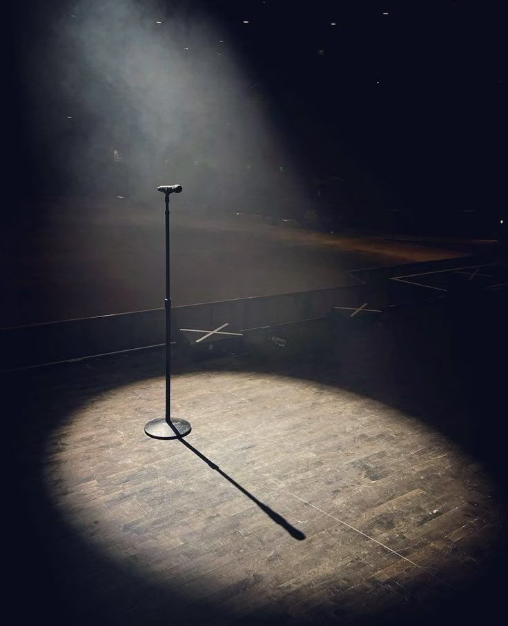 a light shines on the floor in front of a pole with a microphone attached to it