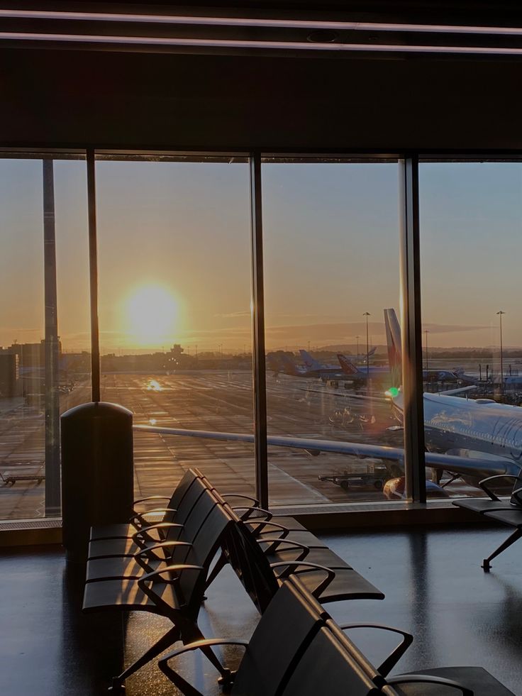 the sun is setting at an airport with many planes parked in the terminal and waiting for their next flight