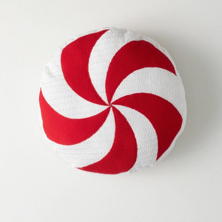 a red and white peppermink pillow on a white surface