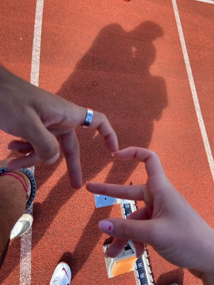 on red track with hand hearts Track And Field Couple Goals, Sport Couple Aesthetic, Xc Couples, Track Couple Pictures, Couples Running Aesthetic, Track And Field Couples, Running Couple Aesthetic, Couple Athlete, Couple Running Aesthetic