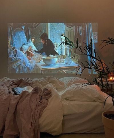 a woman sitting on a bed in front of a tv