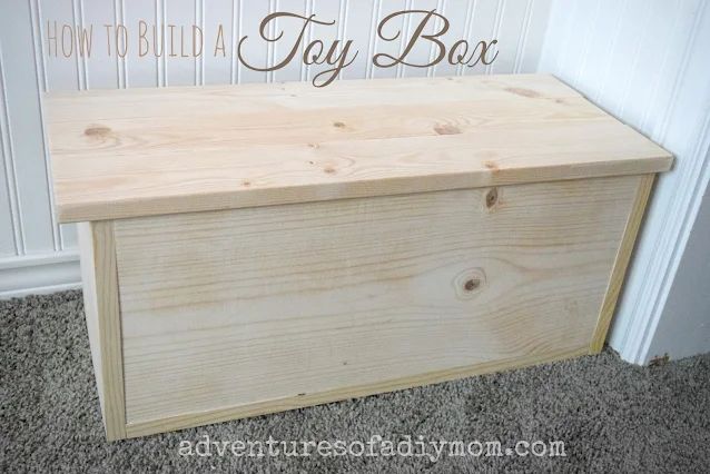 a wooden box sitting on top of carpeted floor next to a wall with the words how to build a toy box