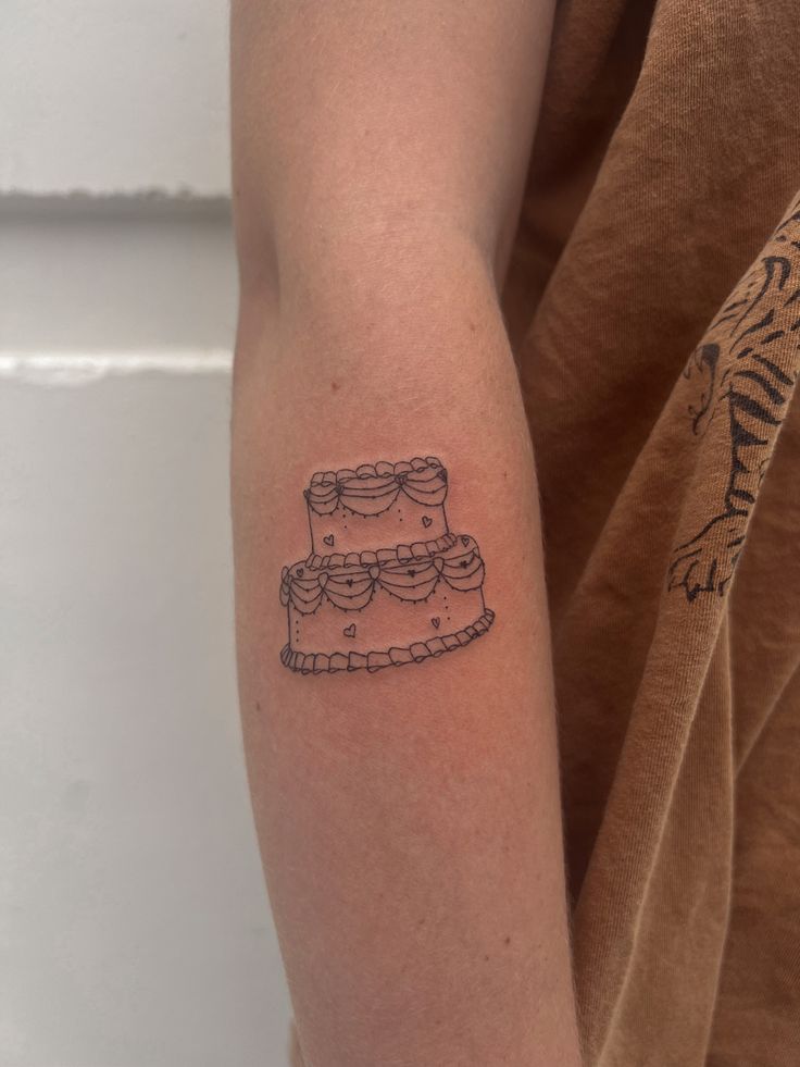 a person with a tattoo on their arm has a cake in the shape of glasses