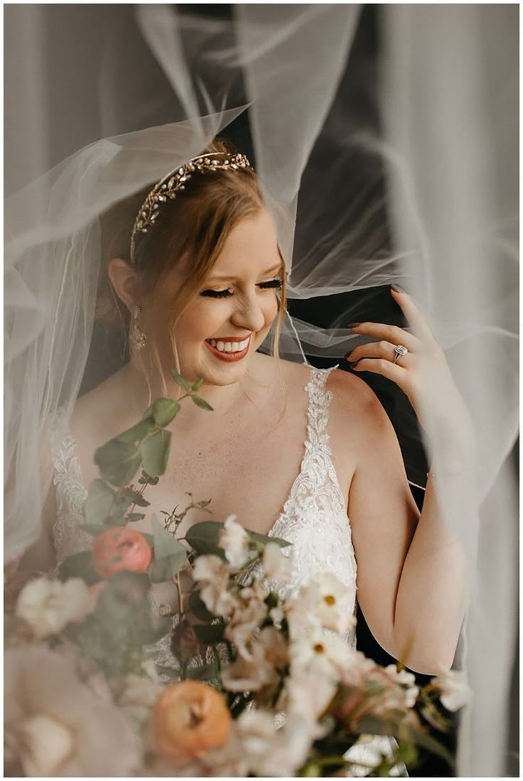 the bride smiles as she holds her veil over her head