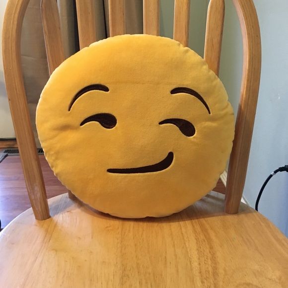 a smiley face pillow sitting on top of a wooden chair