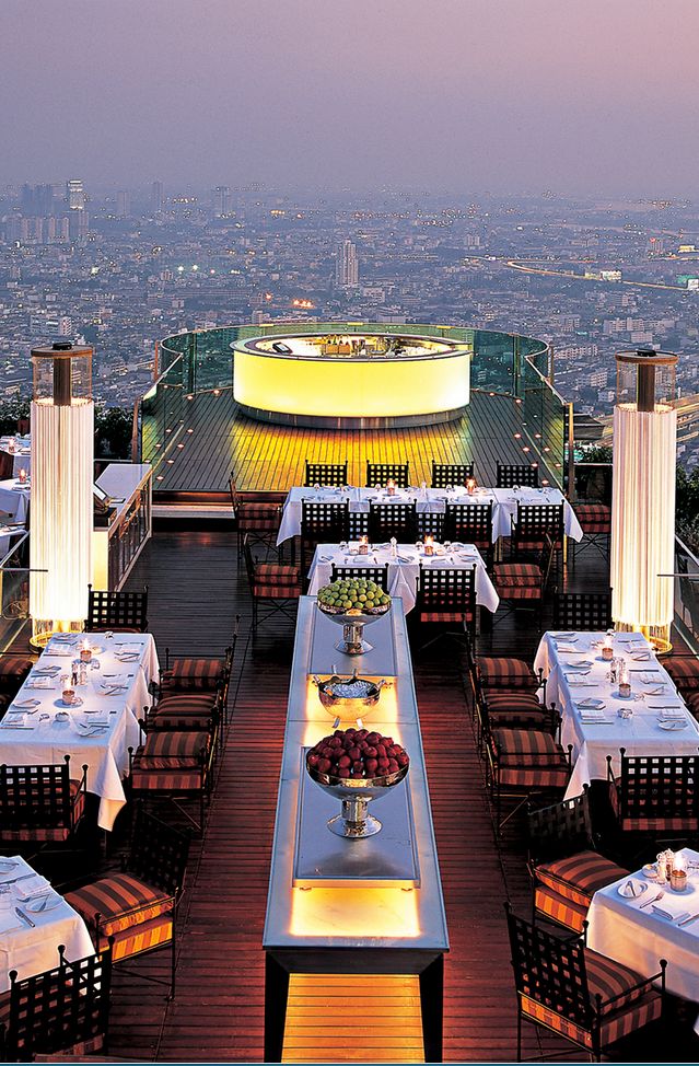 an outdoor dining area overlooking the city at dusk