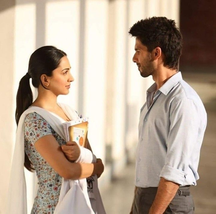 a man standing next to a woman in a dress and holding a book on the street