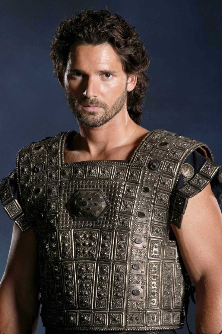 a man dressed in roman armor and holding his hands behind his back, looking at the camera