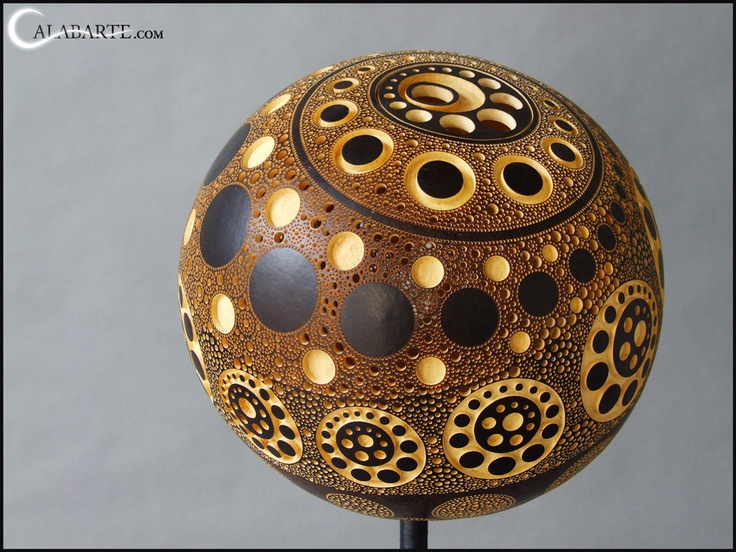 a decorative ball is sitting on top of a metal stand with holes and circles painted on it