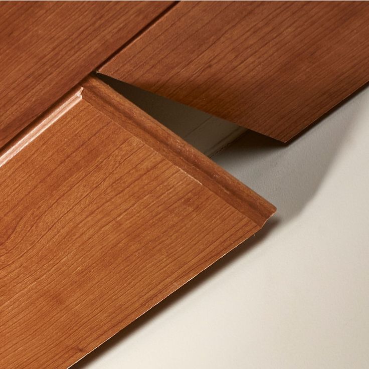 the corner of a wooden cabinet with white walls and wood grains on it's edges