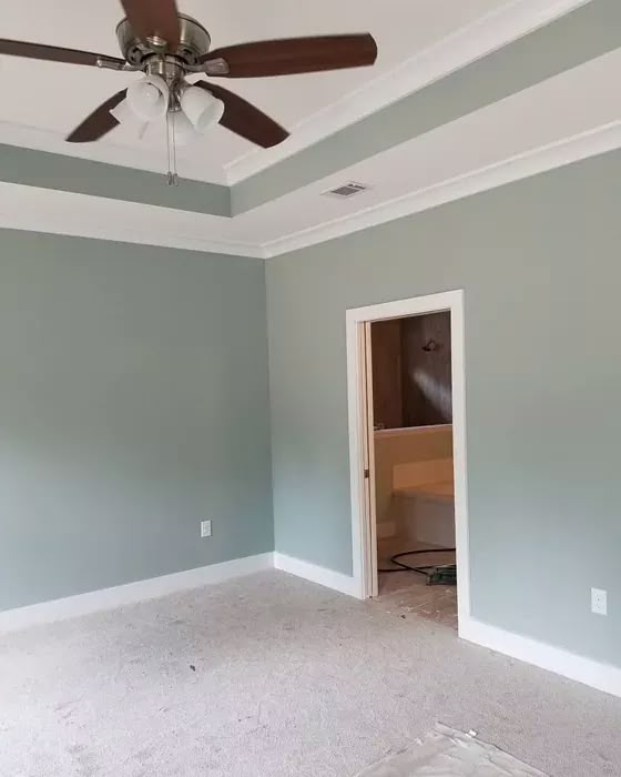 an empty room with a ceiling fan in the corner and carpet on the floor next to it