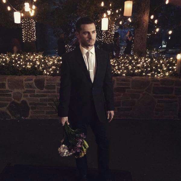 a man in a suit and tie is standing outside at night with lights behind him