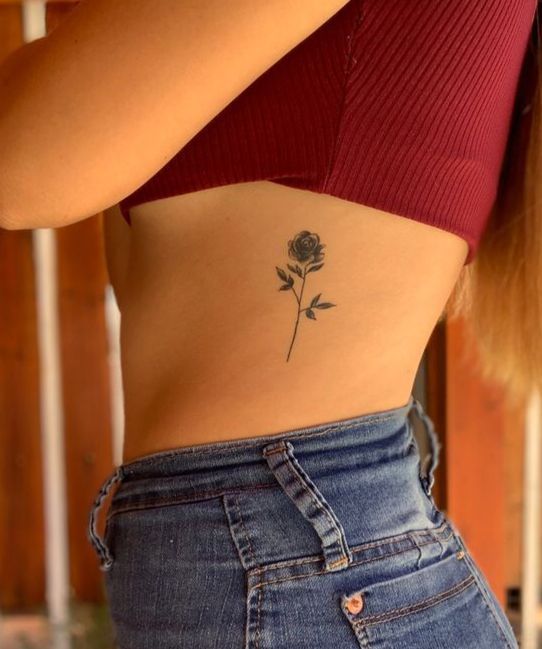 a woman with a rose tattoo on her lower back and the upper half of her stomach