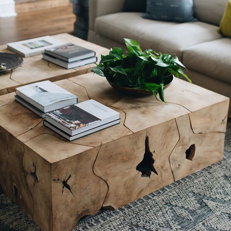 a wooden table with books and a potted plant on it in front of a couch