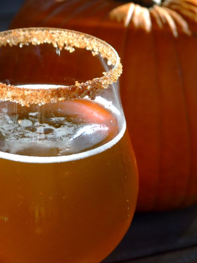 a glass filled with liquid next to a pumpkin