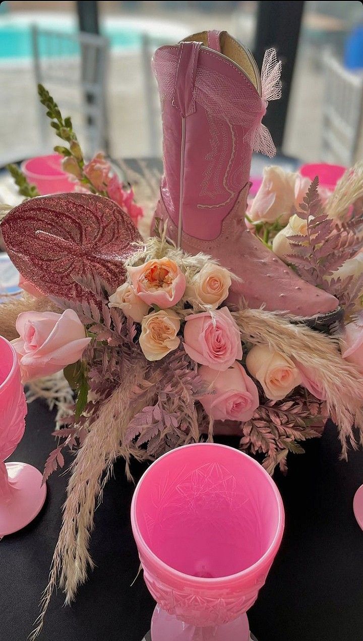 a table topped with pink vases filled with flowers next to a black table cloth