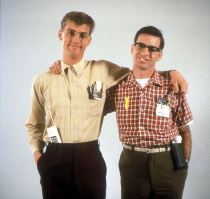 two men standing next to each other with their arms around one another, both wearing glasses