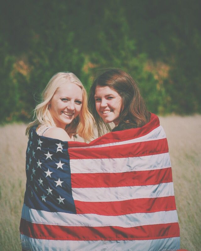 two women holding an american flag in a field