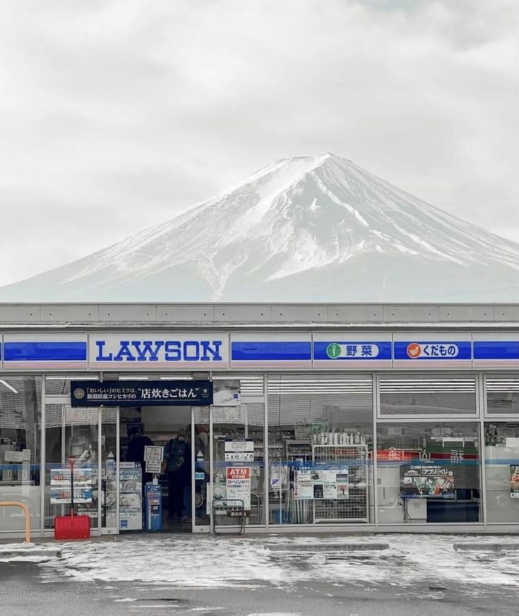 an empty parking lot in front of a building with a snow covered mountain behind it