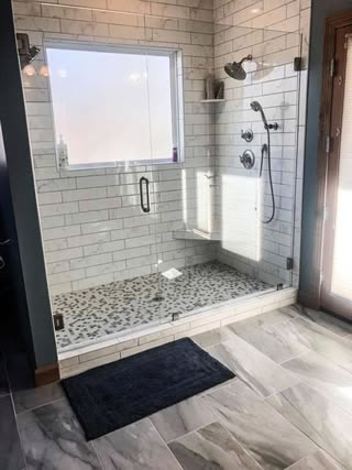 a walk in shower sitting inside of a bathroom next to a door and window on the wall