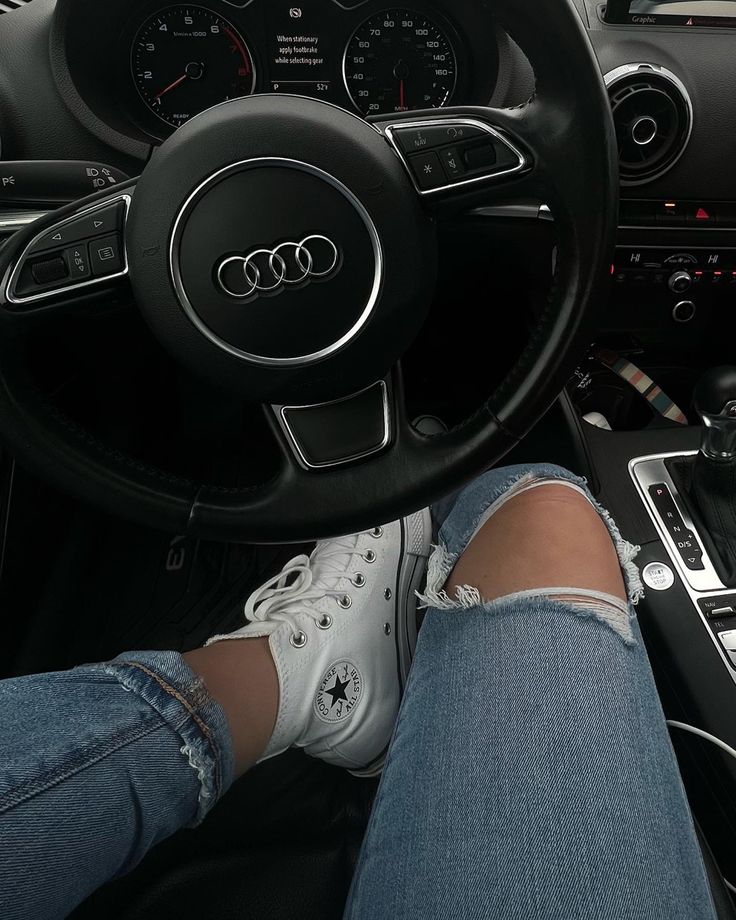 a person sitting in the driver's seat of a car with their feet on the steering wheel