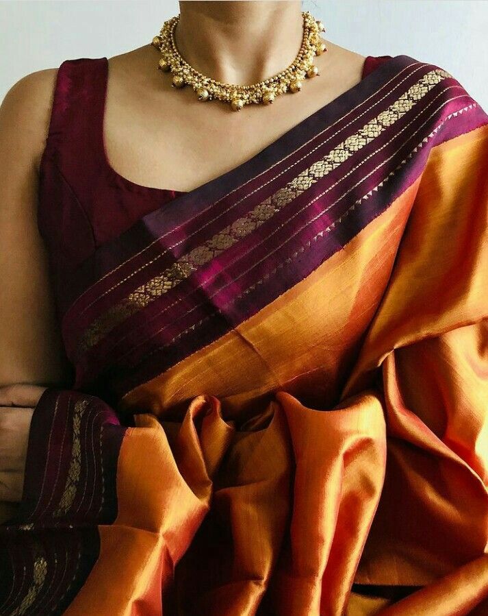 a woman wearing an orange and purple saree with gold jewelry on her neckline