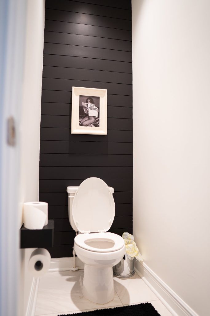 a white toilet sitting in a bathroom next to a black and white wall with pictures on it