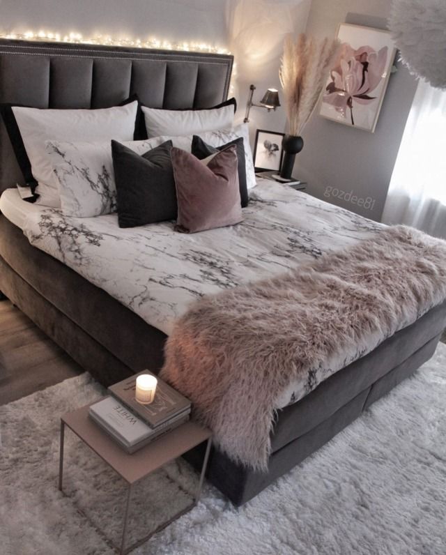 a large bed with white and grey sheets, pillows and blankets on it's headboard