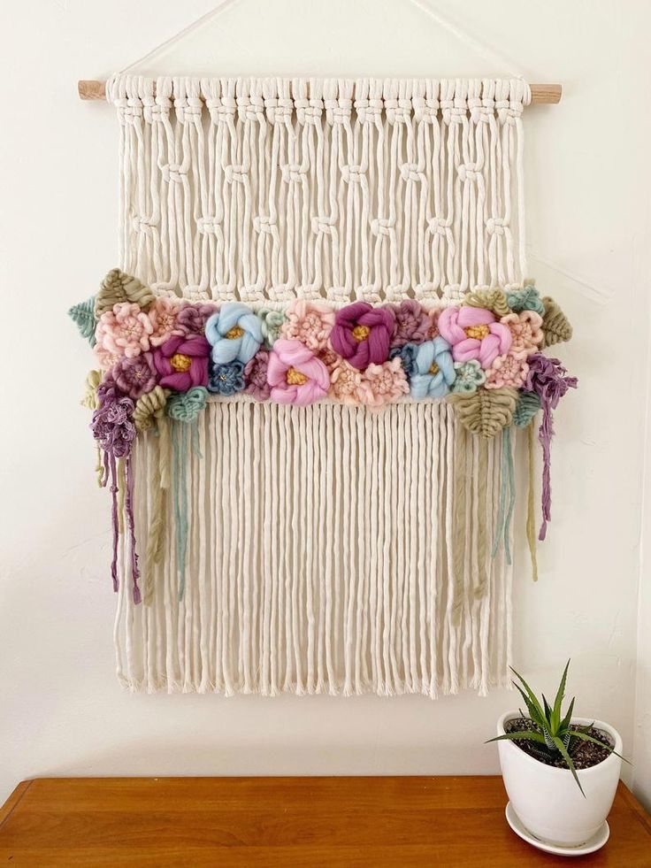 a macrame wall hanging with flowers on it