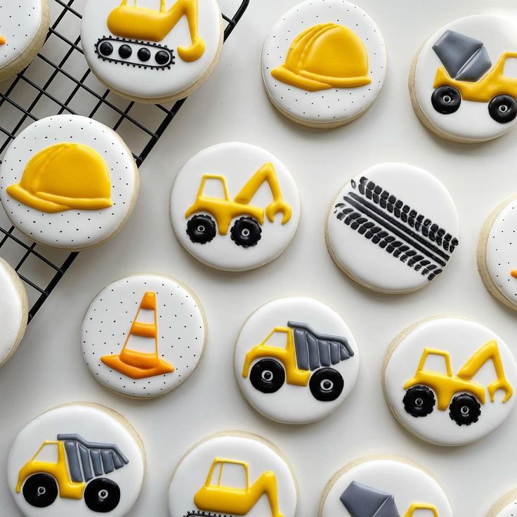 decorated cookies with construction themed icing are on a cooling rack and next to the cupcakes