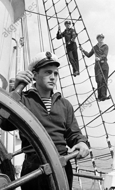 black and white photograph of men on the deck of a ship, with ropes in front of them