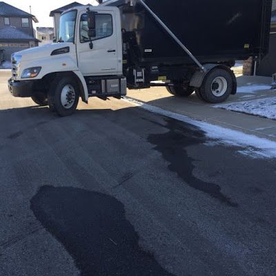 a dump truck parked on the side of a road in front of a house with snow on the ground