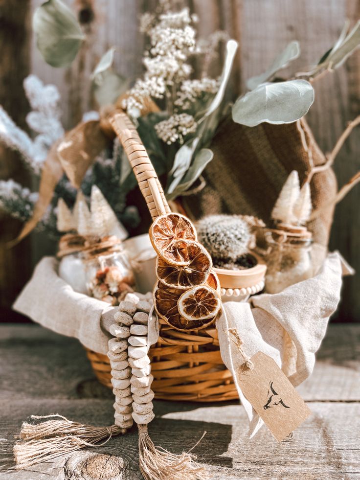 a wicker basket filled with lots of dried flowers and other things sitting on top of a wooden table