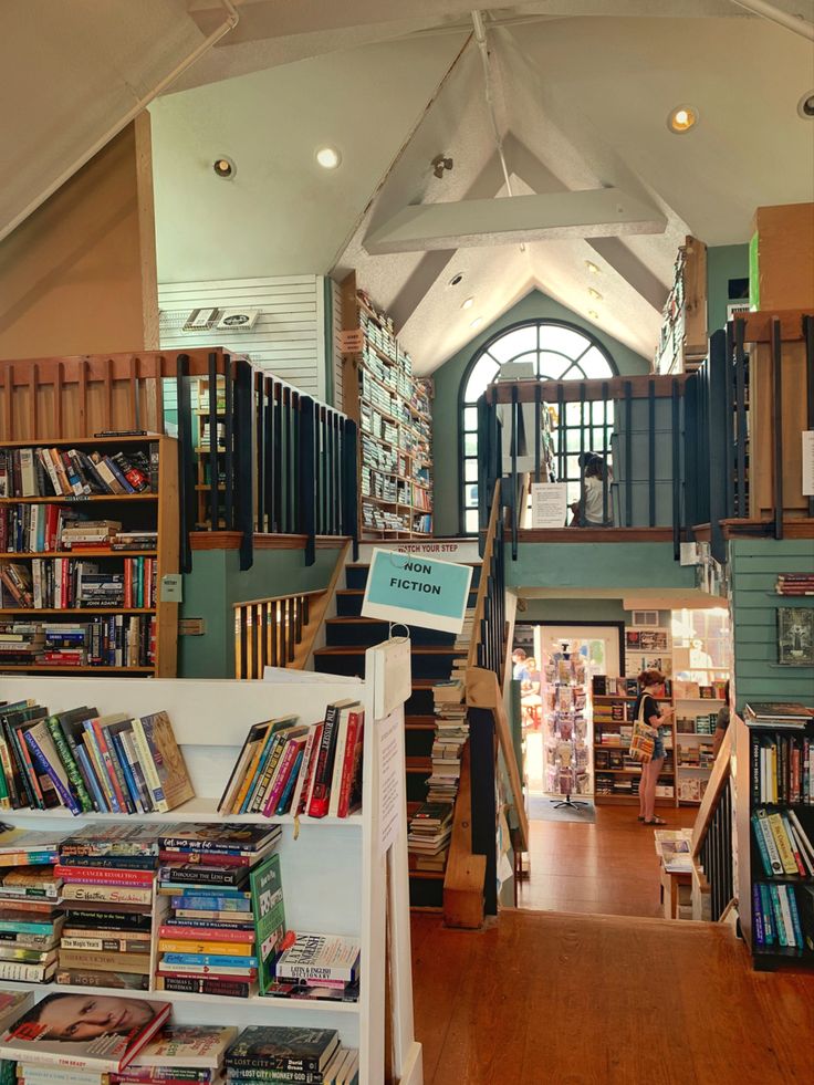 the inside of a bookstore with lots of books on shelves and stairs leading up to the second floor