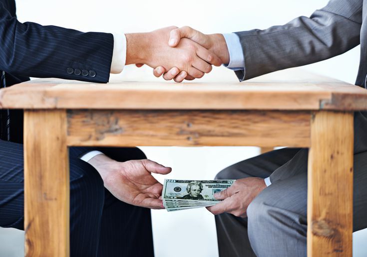 two men shaking hands over a wooden table