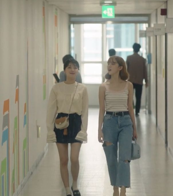 two young women walking down a long hallway