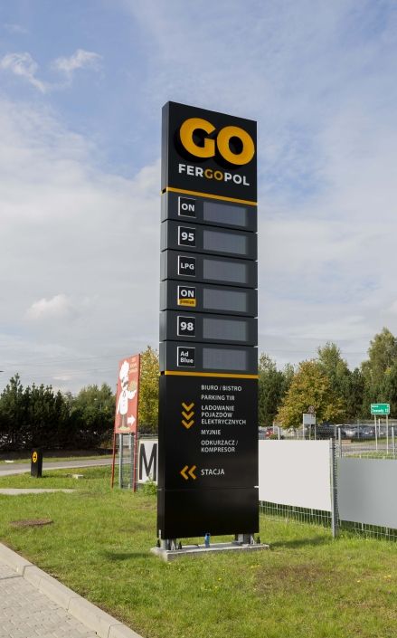 a large sign in front of a fenced off area with grass and signs on it