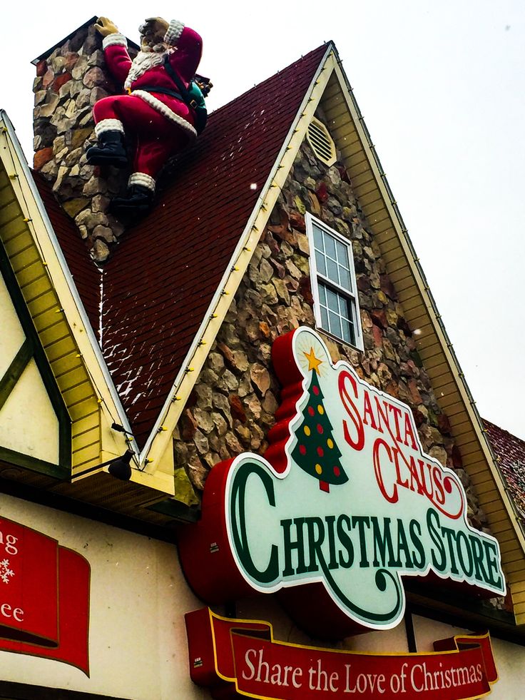 santa clause's christmas store sign on the side of a building with a giant teddy bear