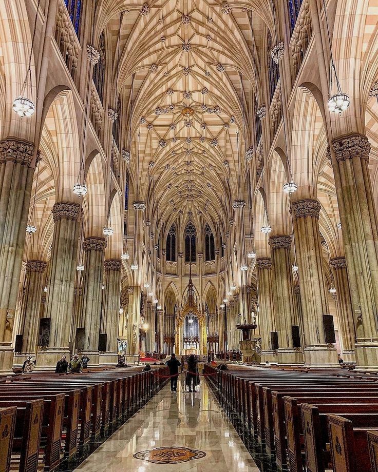 the inside of a large cathedral with pews and people walking through it on either side