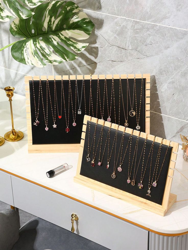 two wooden jewelry racks with necklaces hanging from them on top of a white table