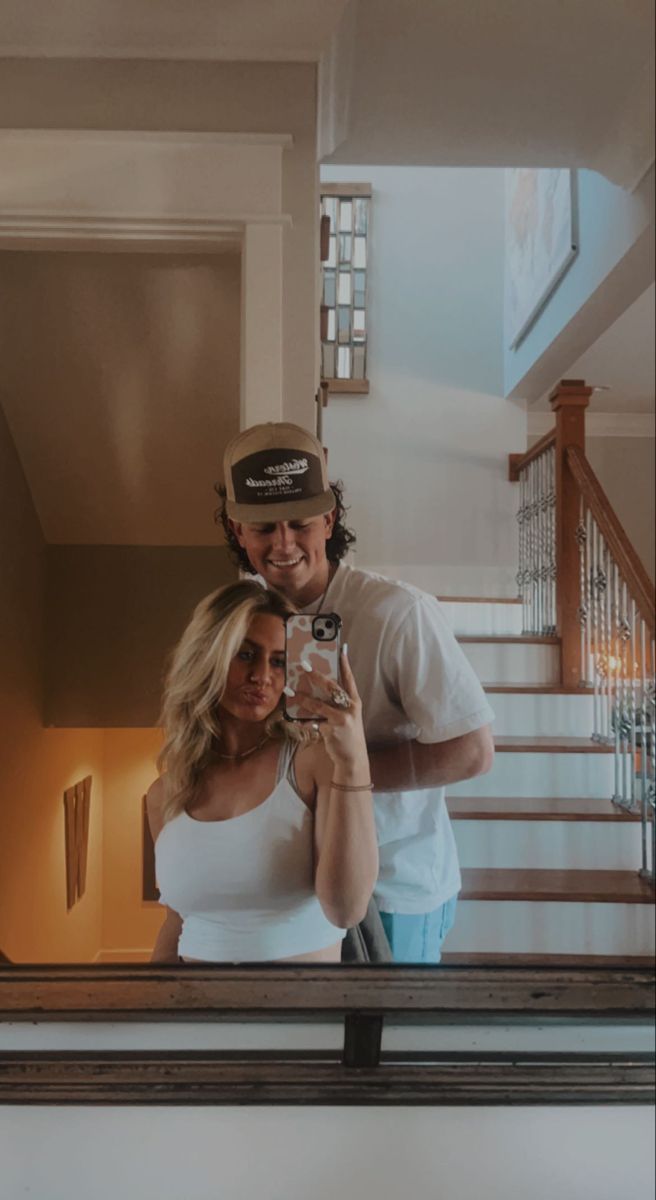 a man and woman taking a selfie in front of stairs with their cell phone