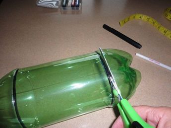 someone is cutting through the bottom of a green glass bottle with scissors and measuring tape