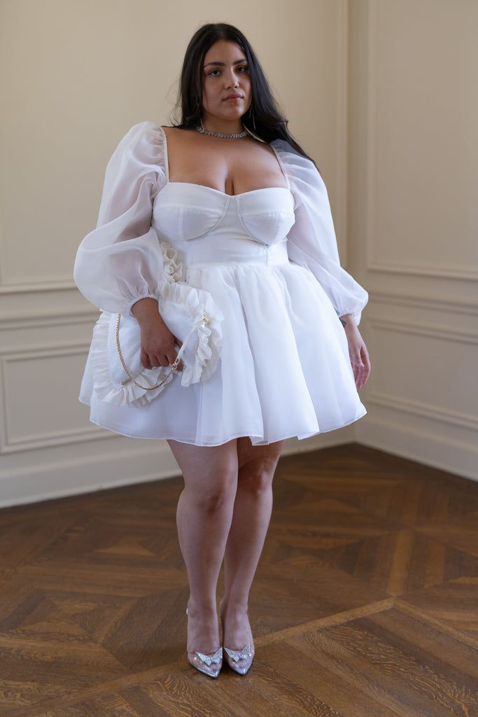 a woman in a white dress posing for the camera with her hands on her hips