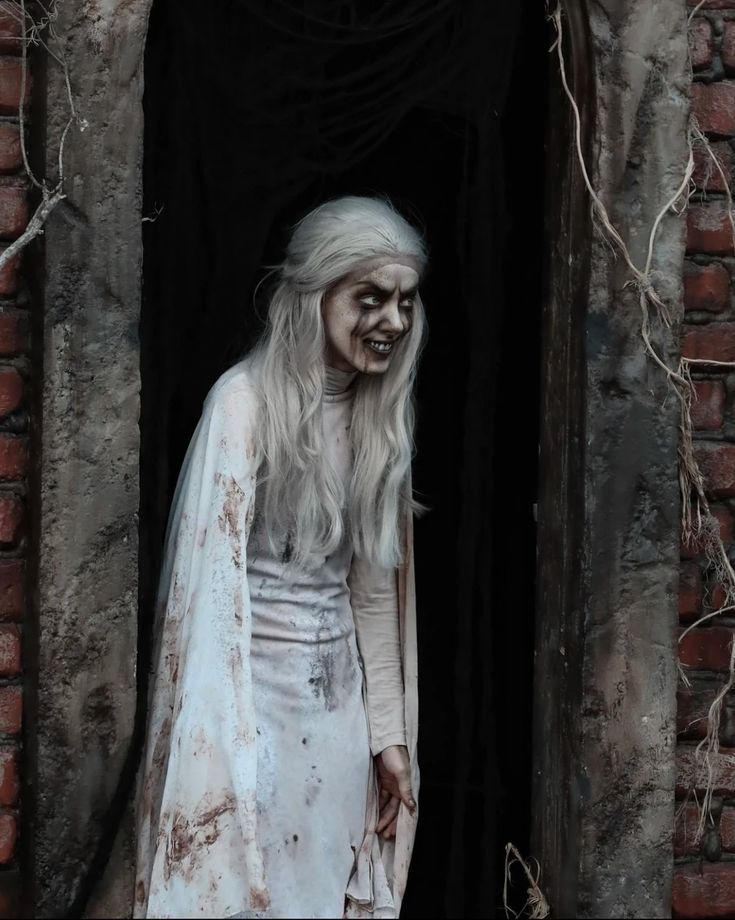 a woman dressed in white is walking out of a brick building with blood on her face